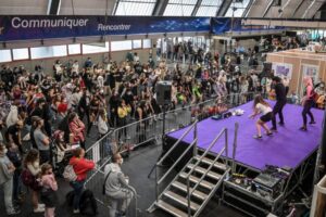 Performance de danse K-pop sur scène violette devant une foule nombreuse au Toulouse Game Show Pau