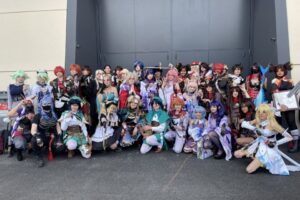 Grand groupe de cosplayeurs déguisés en personnages de Genshin Impact posant devant le hall du TGS Montpellier